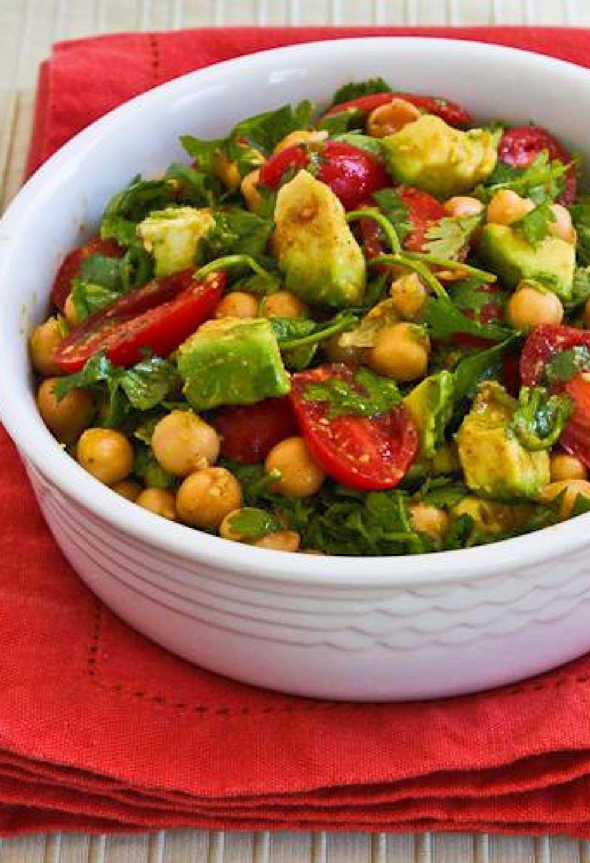 Chickpea Tomato Salad vertical image of one serving of salad on red napkin