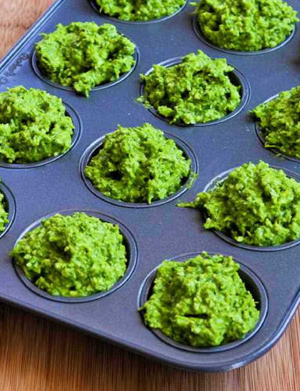 vertical photo of Garlic Scape Pesto with Chard in muffin tins ready for freezer