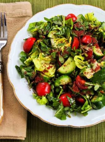 Purslane Salad with Lettuce, Tomatoes, Cucumbers, and Mint shown on salad plate with fork and napkin.