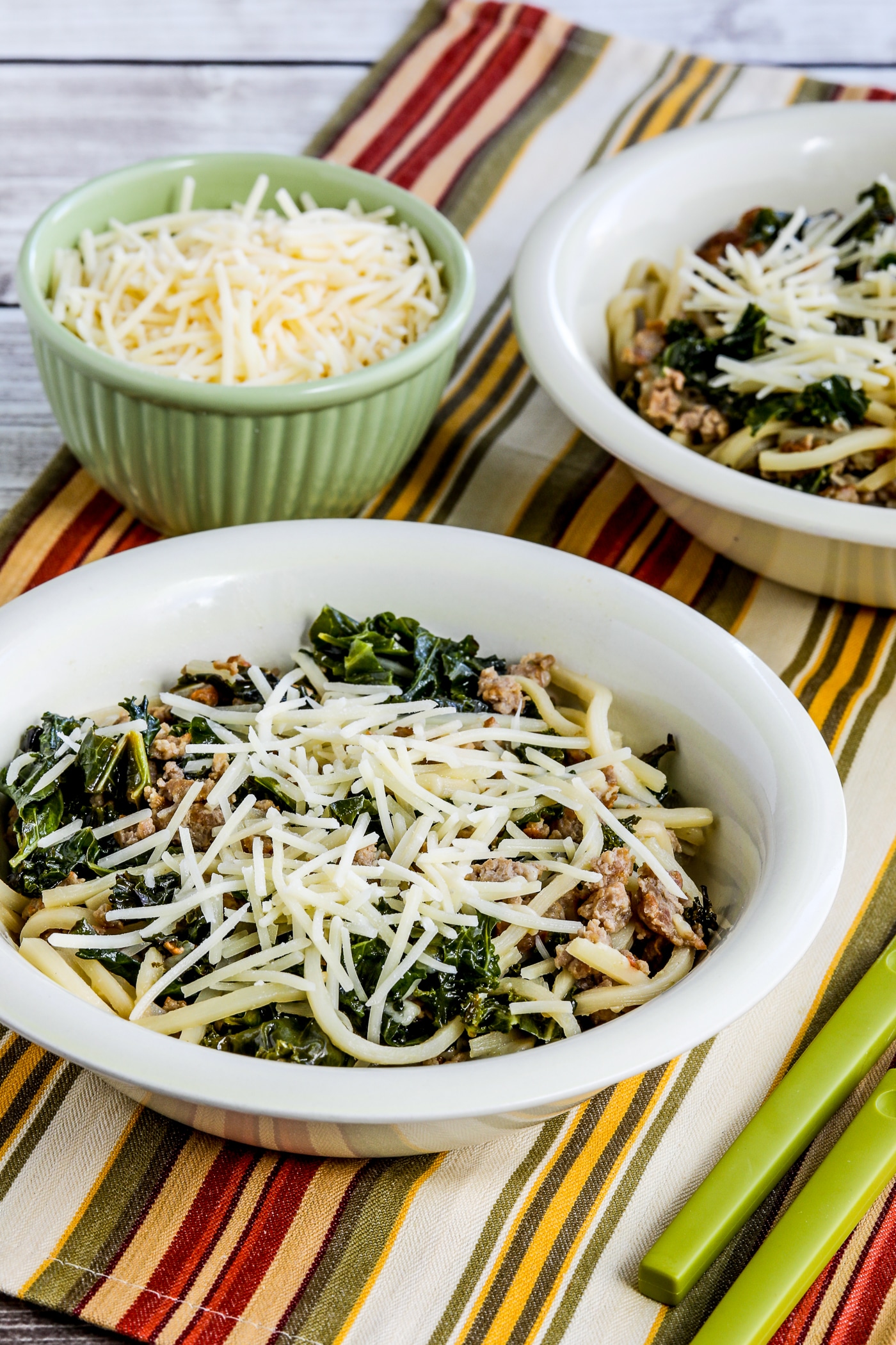 Pasta with Sausage and Kale finished dish shown in two serving bowls with Parmesan