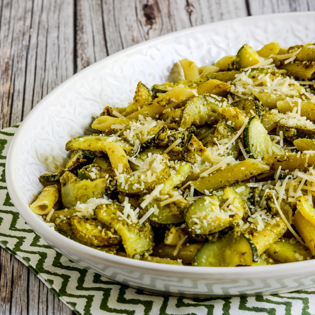 Zucchini pesto pasta in a serving bowl on a green-white napkin