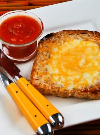 Square image of Cheesy Eggs in a Hole on serving plate with salsa.