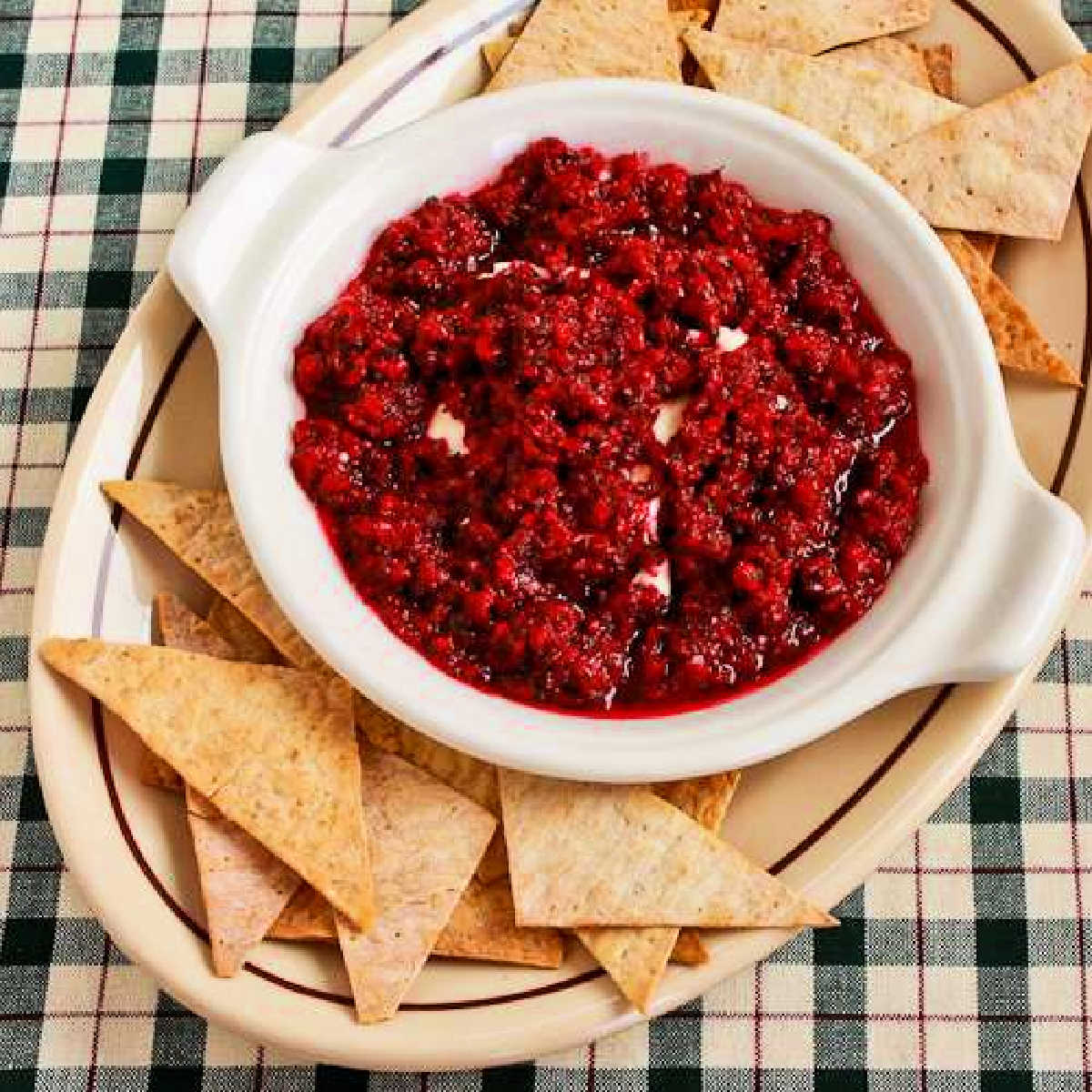 Square image of Cranberry Cream Cheese Dip shown on plate with chips.