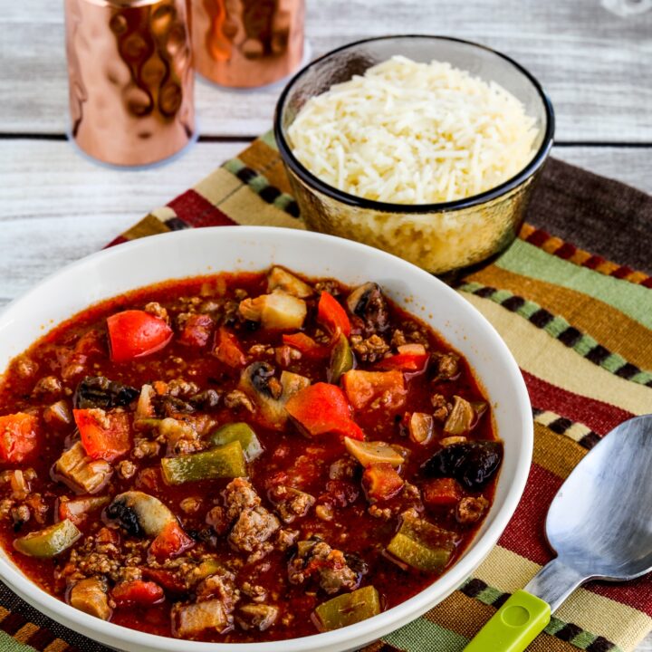 Italian Sausage Stew in serving bowl with spoon, salt-pepper shakers, and Parmesan