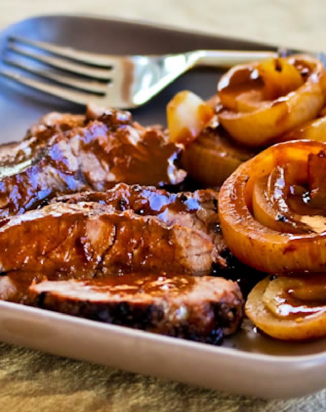 Slow Cooker Balsamic Pot Roast shown on serving plate with onions and fork in back.
