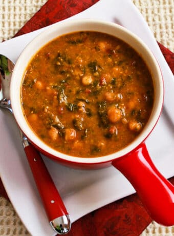 Square image for Tomato Chickpea Soup shown in bowl on plate with spoon.
