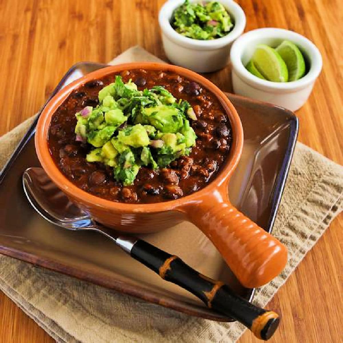Square image for Black Bean and Beef Chili with avocado salsa, shown in bowl with spoon.