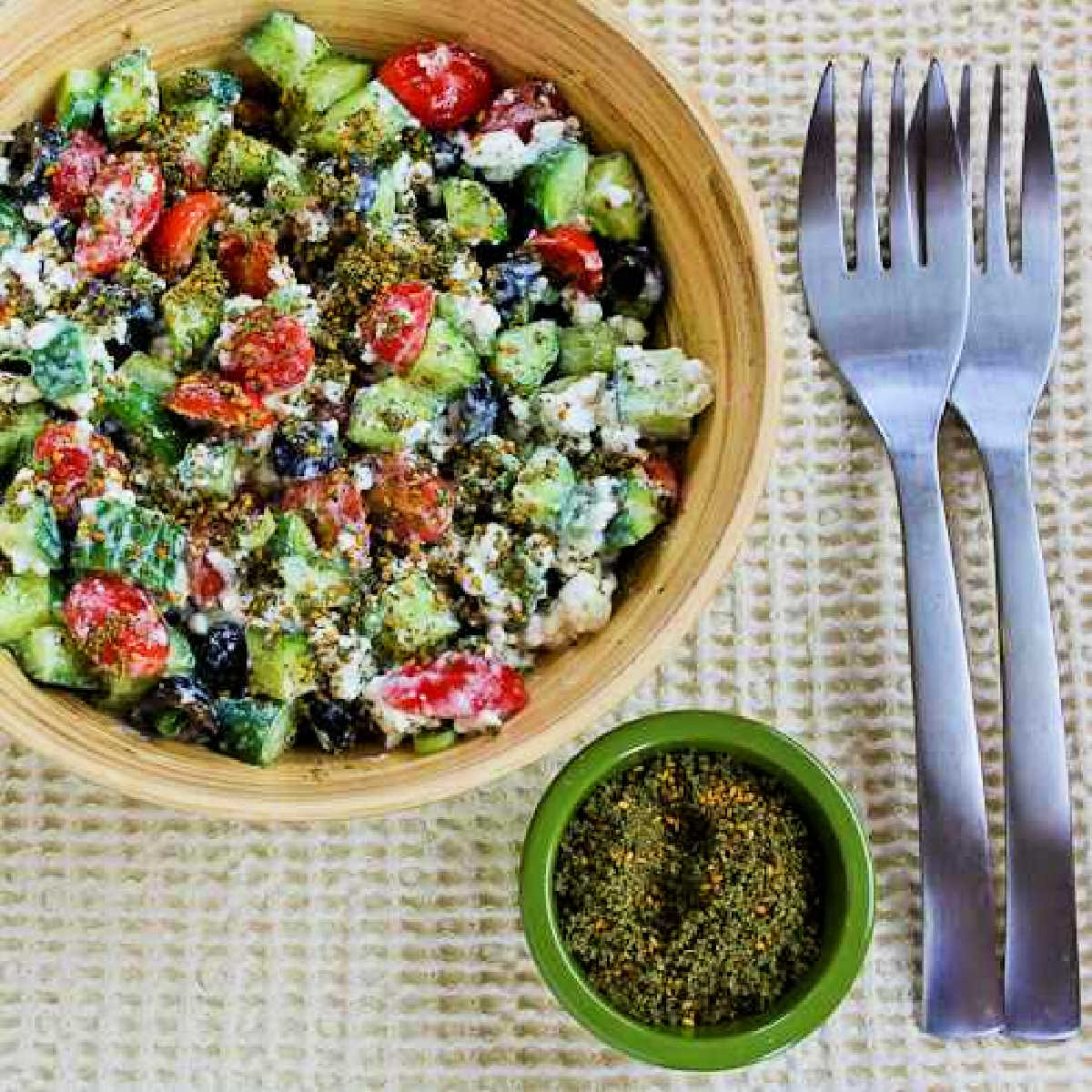 Cottage Cheese Salad with Za'atar shown in serving bowl with Za-atar and forks on the side.
