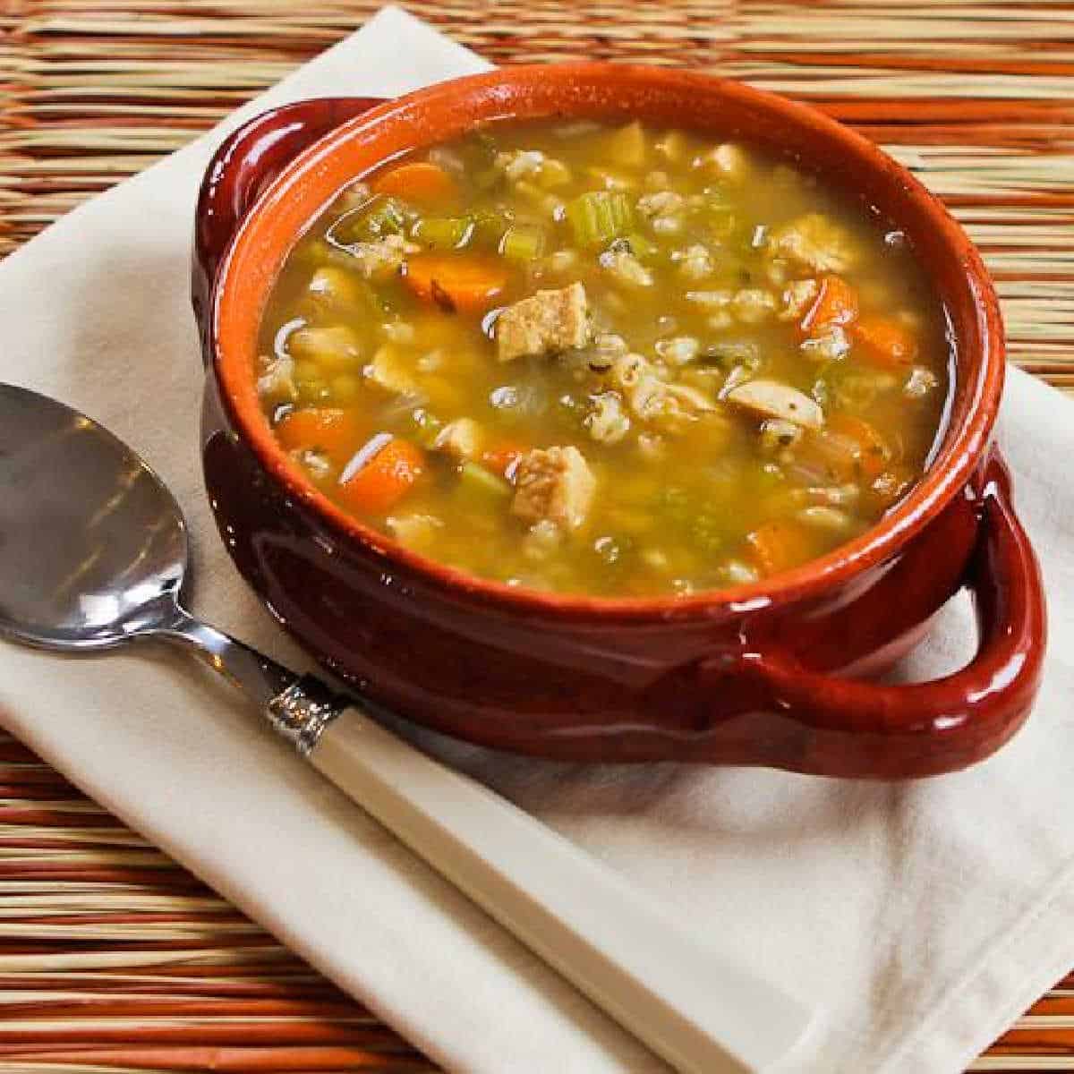 Chicken Barley Soup in two-handled bowl on napkin with spoon