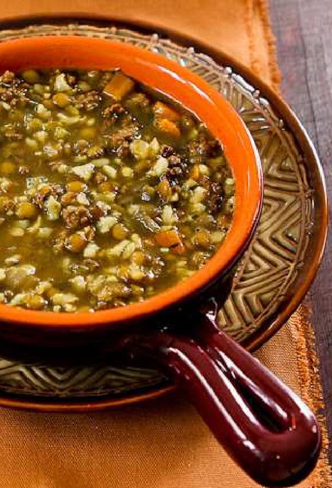 Lentil Soup with Ground Beef shown in bowl on orange napkin.