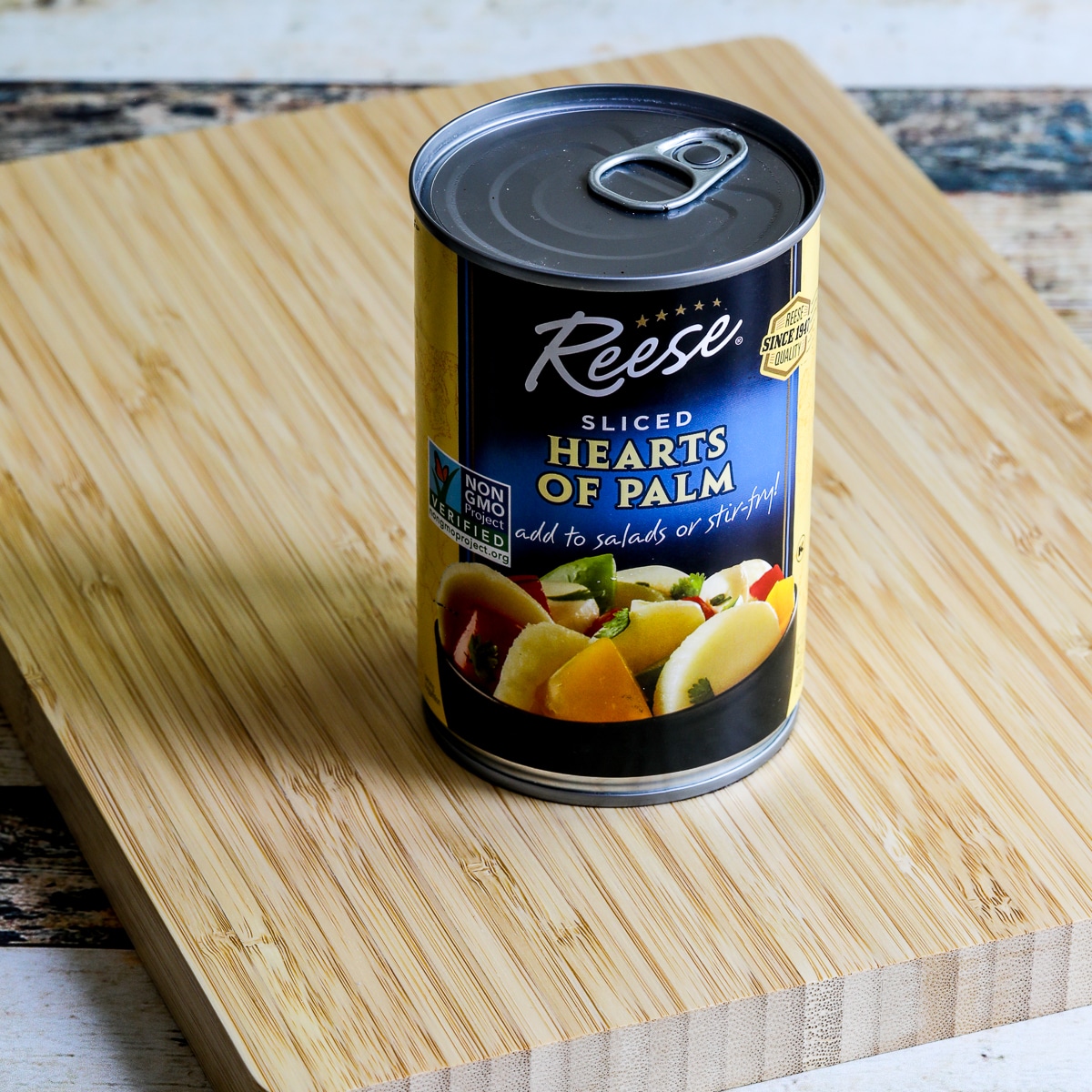 A square image of a can of palm hearts on a cutting board.