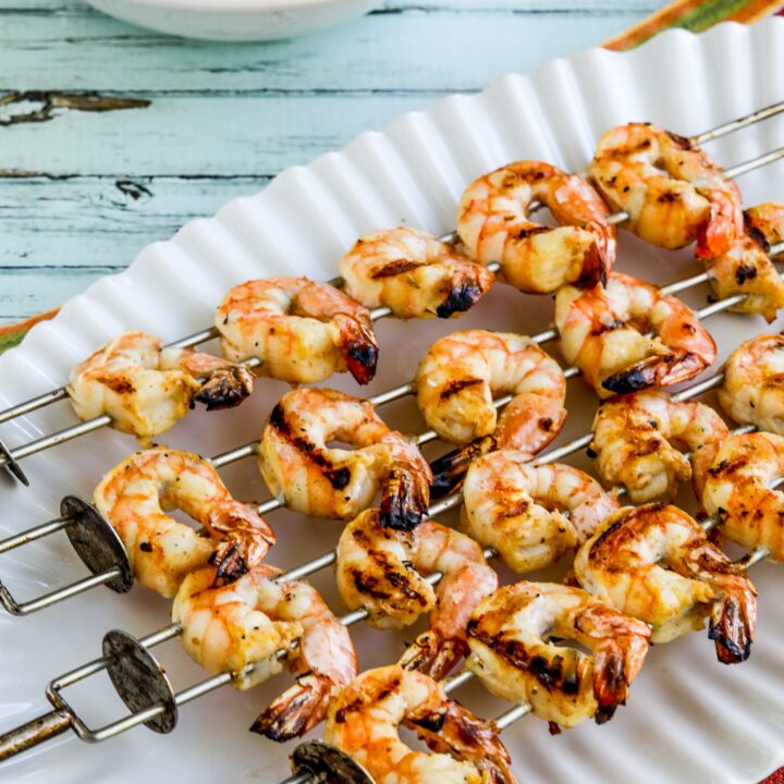 Grilled Shrimp Skewers on serving plate with bowl of tomato-avocado salsa.