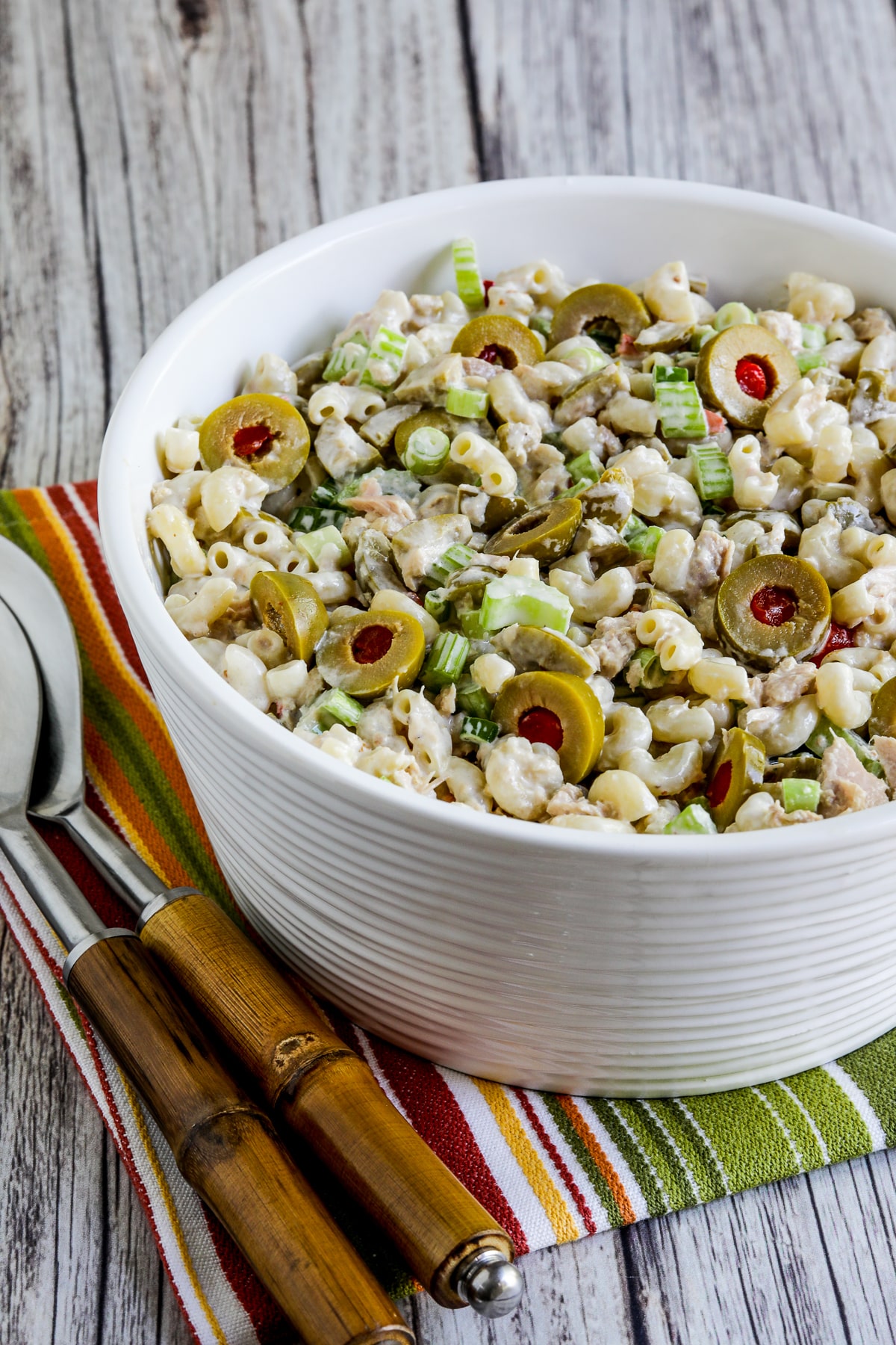 Tuna macaroni salad with green olives is shown in a bowl with a fork.