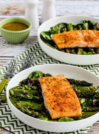 two finished Salmon and Asparagus Salads in serving bowls with dressing and salt-pepper shakers