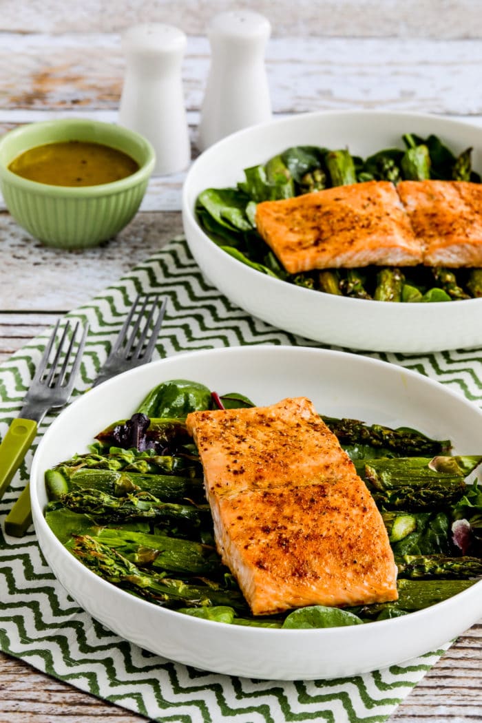 two finished Salmon and Asparagus Salads in serving bowls with dressing and salt-pepper shakers 