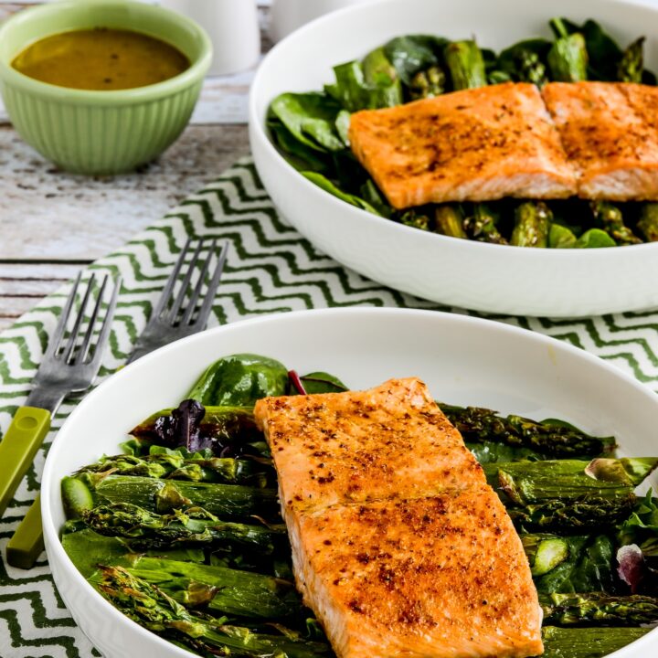 two finished Salmon and Asparagus Salads in serving bowls with dressing and salt-pepper shakers