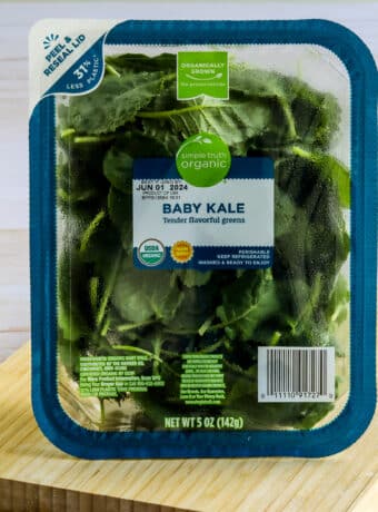 Square image of organic baby kale shown on cutting board.