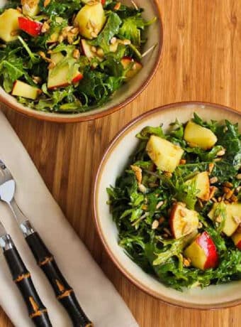 Kale Apple Salad in two bowls with forks and napkins