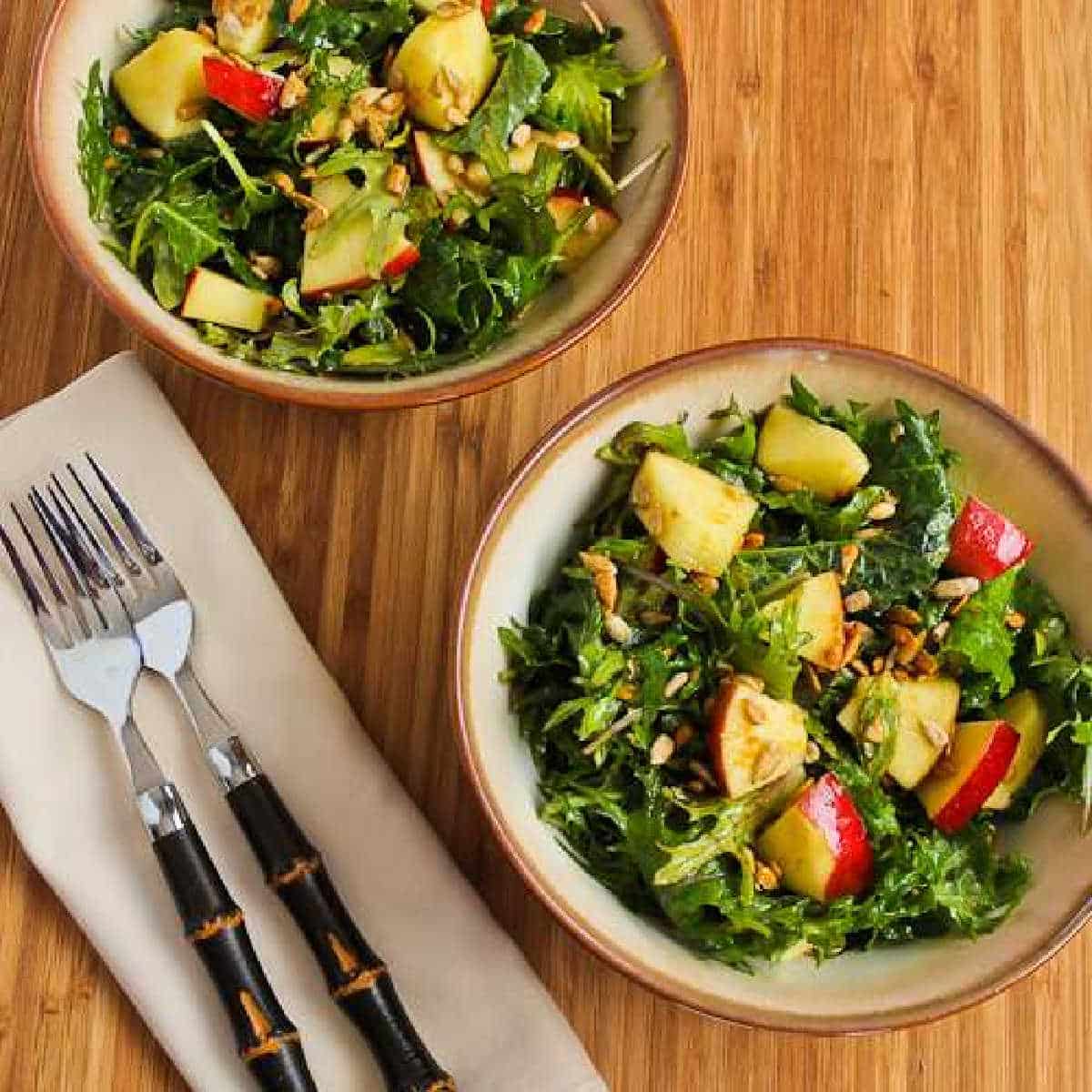 Kale Apple Salad in two bowls with forks and napkins