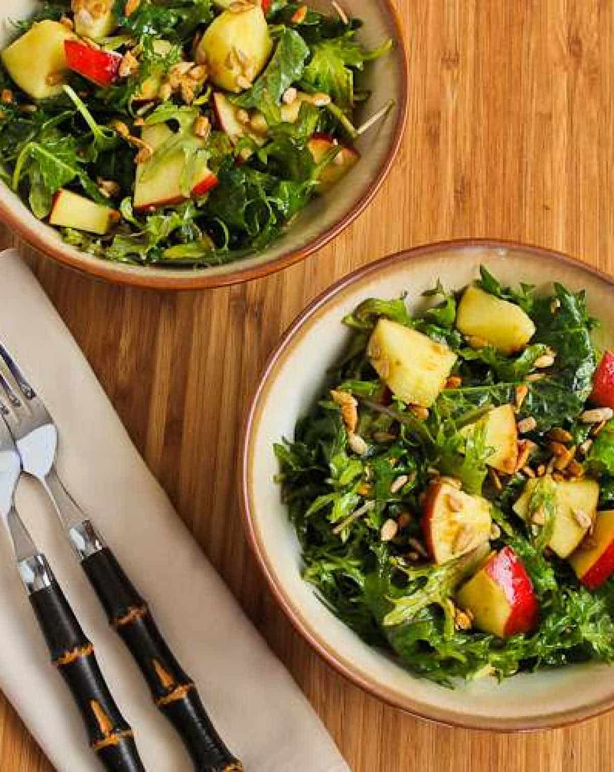 vertical photo of Kale Apple Salad in two bowls with forks