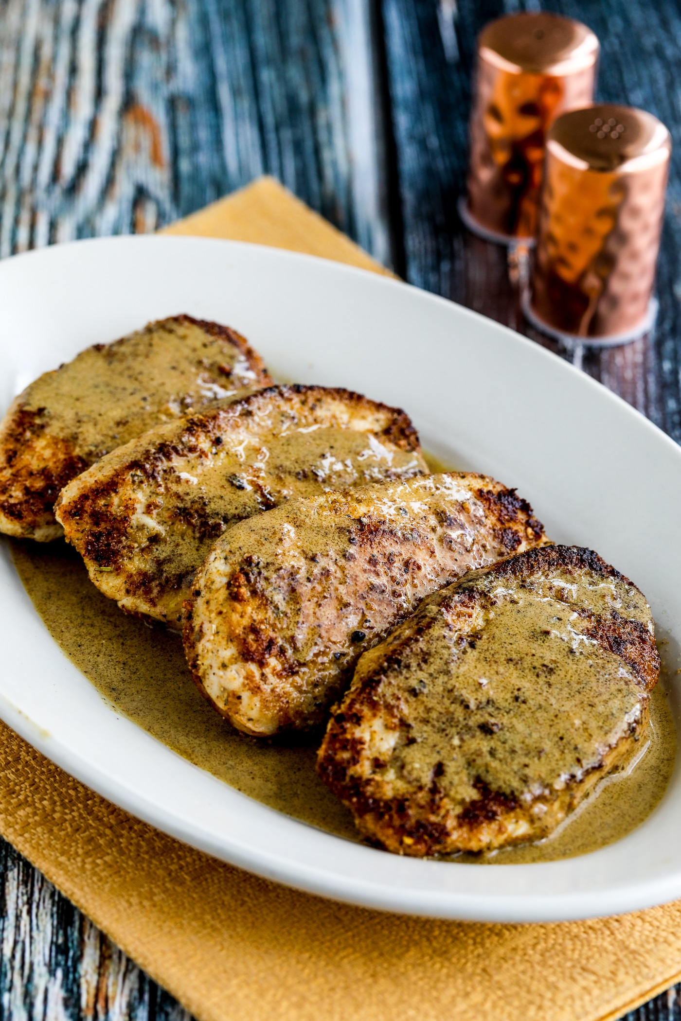 Chicken Cutlets with Mustard Sauce shown on serving plate with salt-pepper in background