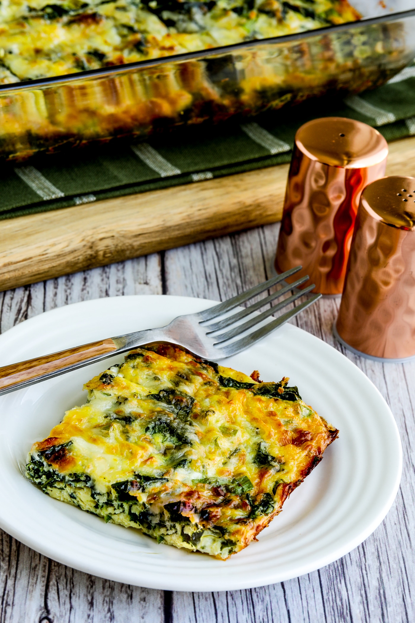 one piece of Kale, Mozzarella, and Egg Bake on plate with casserole dish in background