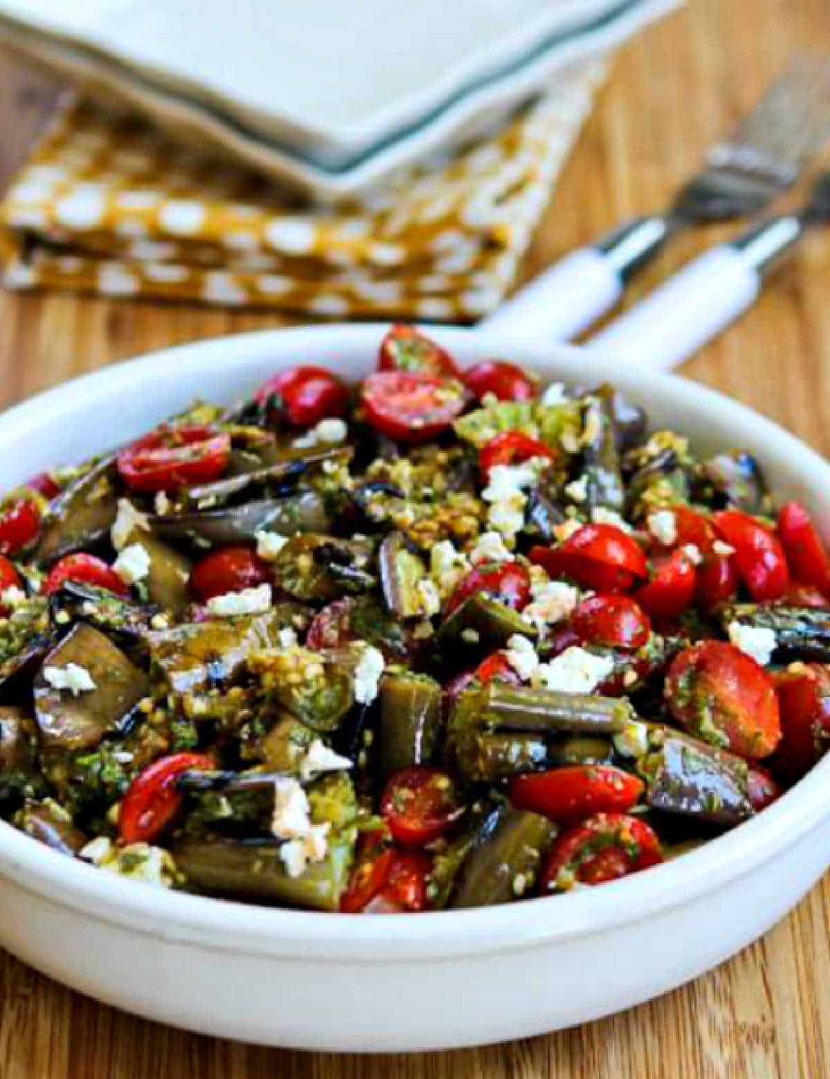 Grilled Eggplant Salad in serving bowl with plates, forks, and napkin in background