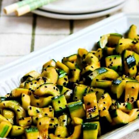 Chinese Cucumber Salad on serving platter with plates and chopsticks.