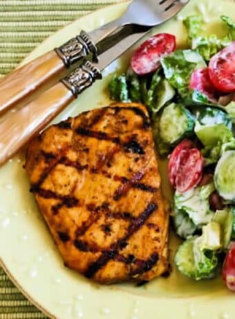Square image of Marinated Grilled Halibut with Cumin and Lime on plate with salad.