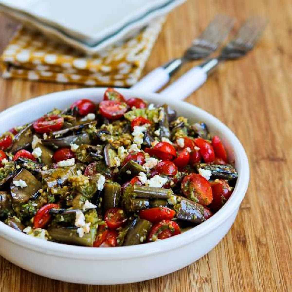 Grilled Eggplant Salad in serving dish with napkin, plates, and forks in background