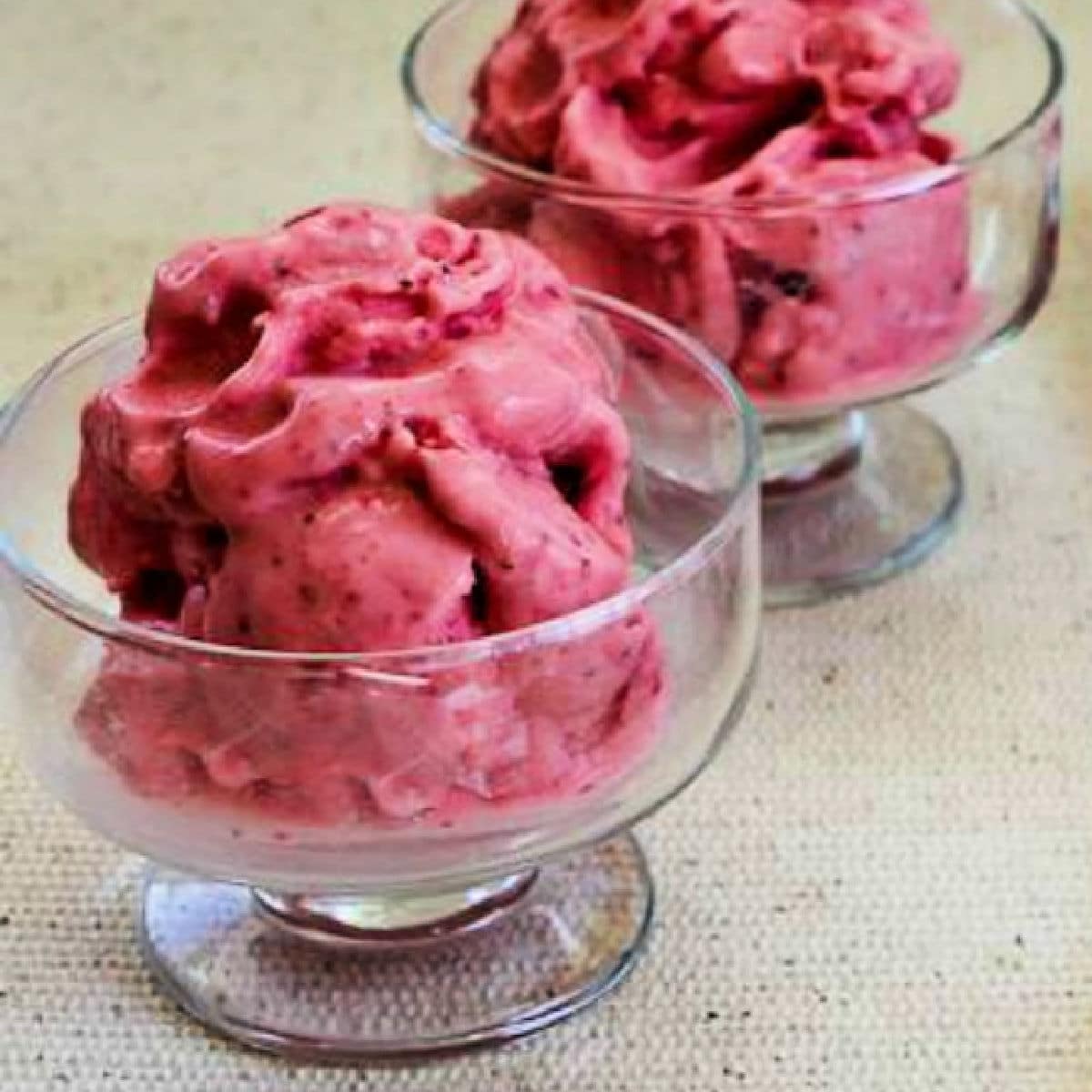 Low-Sugar Strawberry Frozen Yogurt shown in two glass serving dishes.