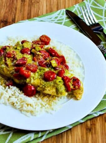 Square image of Baked Fish in Foil with Pesto and Tomatoes on serving plate over rice.