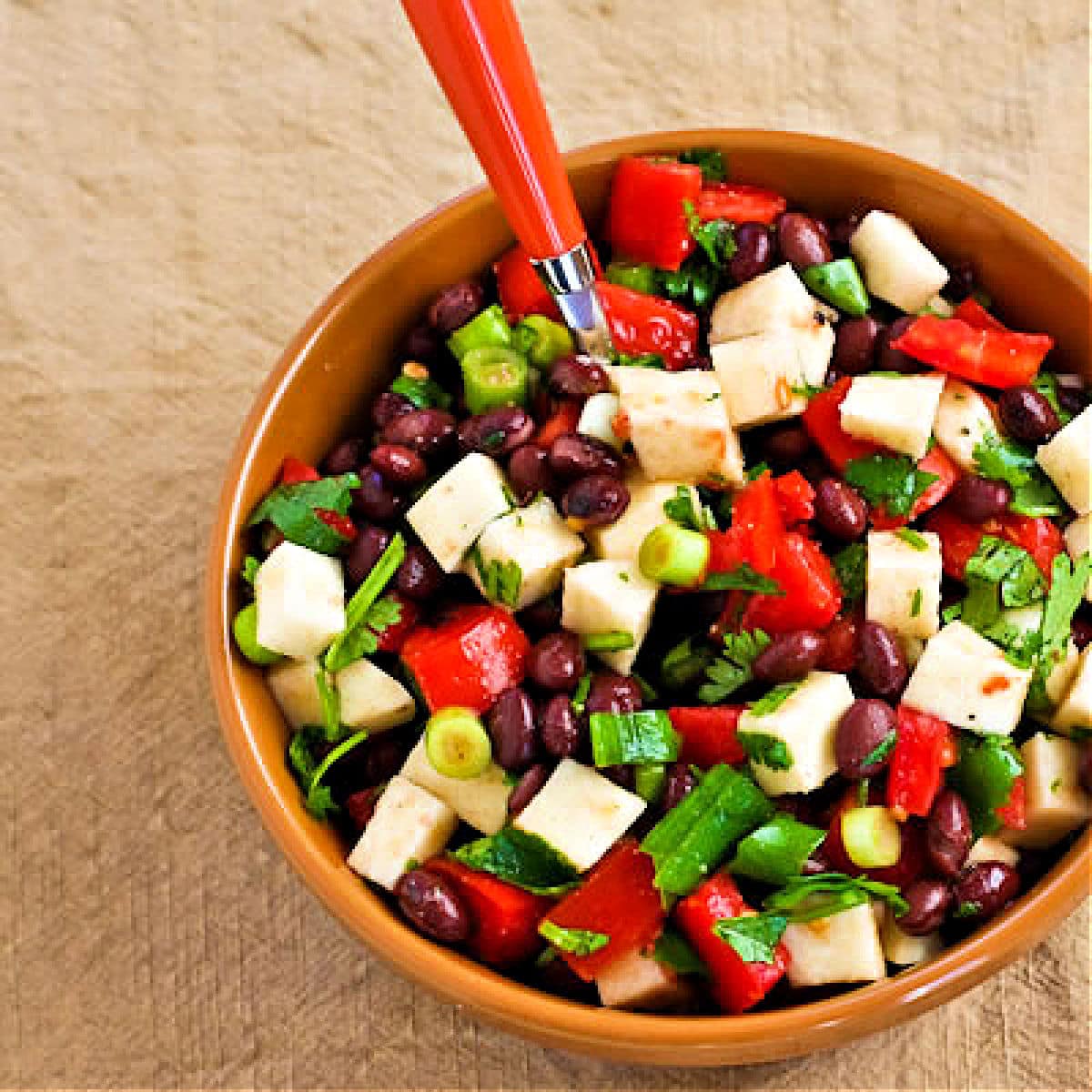 Square image of Black Bean Jicama Salad in serving bowl with fork sticking out.