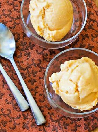 Square image of Fresh Peach Frozen Yogurt shown in two serving bowls with spoons.