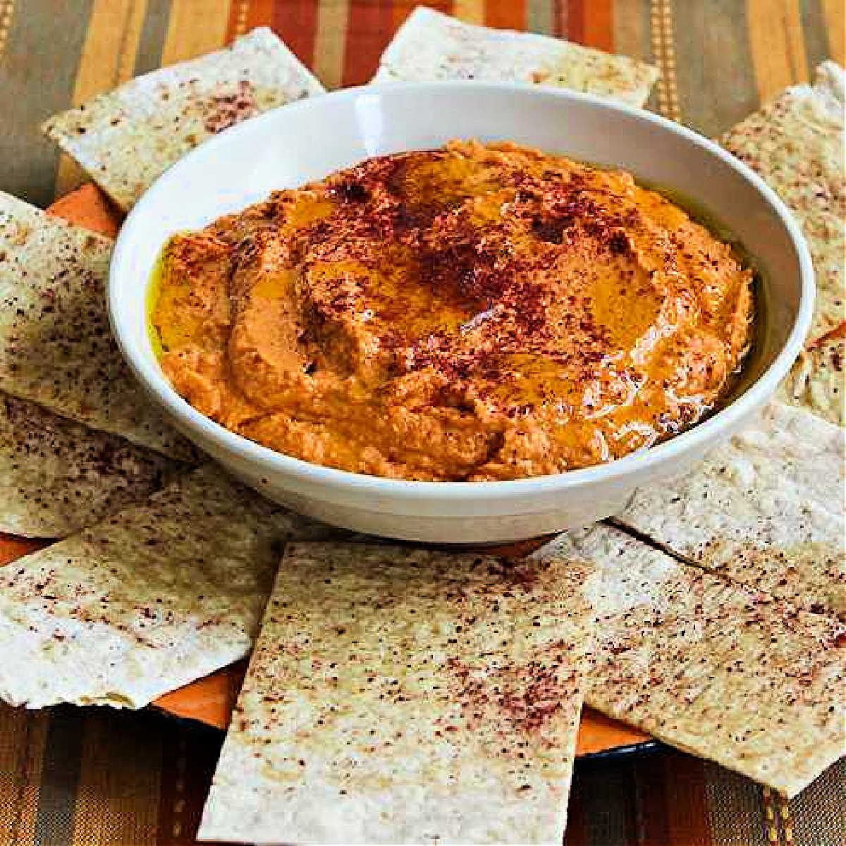 Square image for Roasted Tomato Hummus shown in bowl with pita bread.