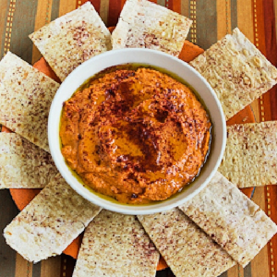 Overhead shot of Roasted Tomato Hummus in bowl with pita bread around it.