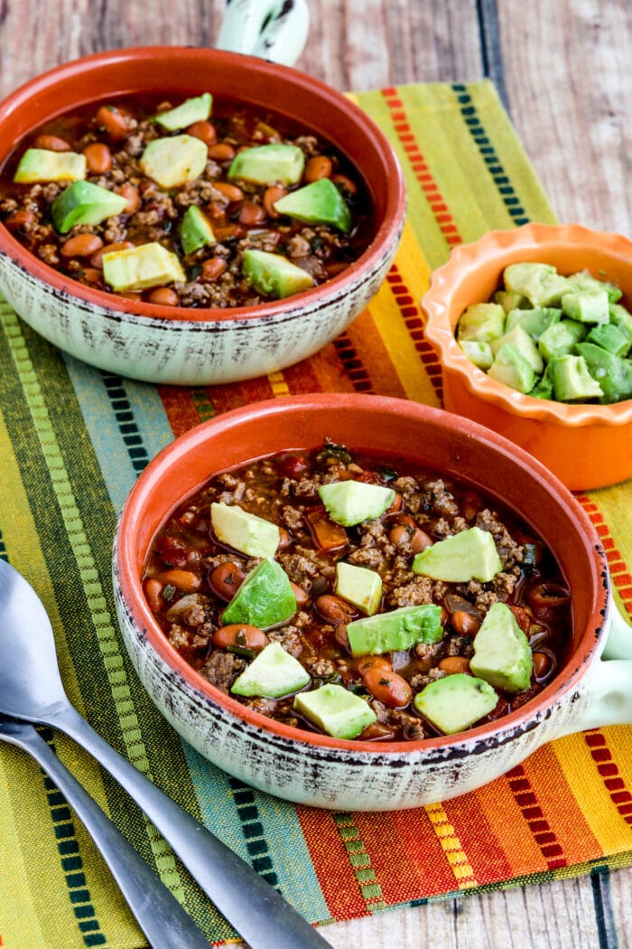 Instant Pot Pinto Beans with Ground Beef in two bowls with colorful napkin and avocado