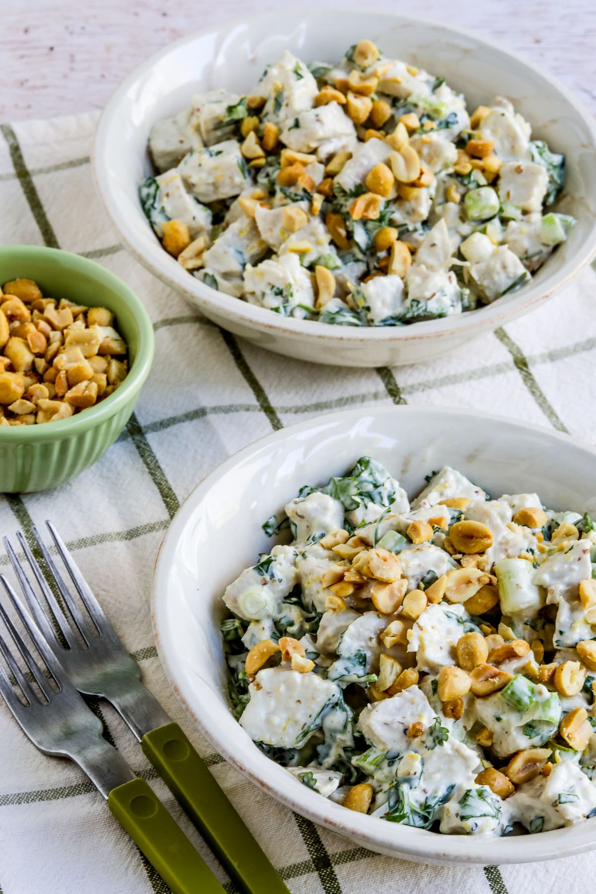 Spicy Chicken Salad with Ginger and Lemon shown in two bowls with forks and bowl of peanuts.