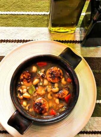 Square image of Black-Eyed Pea Soup shown in bowl with olive oil and sherry vinegar in background.