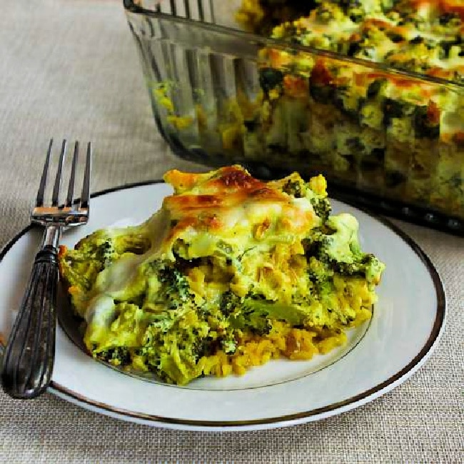 Broccoli and Rice Casserole on serving plate with fork and baking dish in background