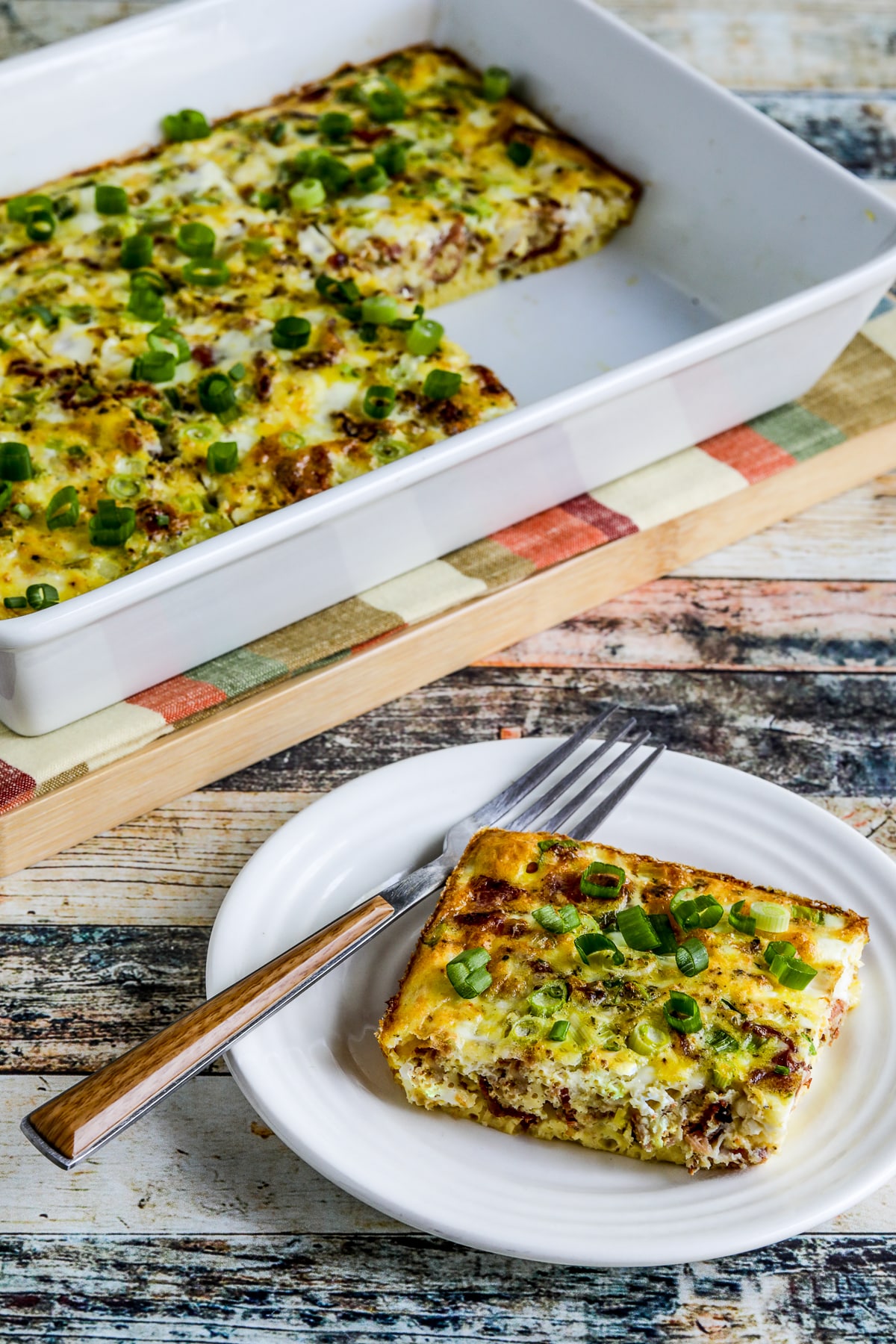 Bacon Feta Breakfast Casserole with one serving on small plate and baking dish in background.