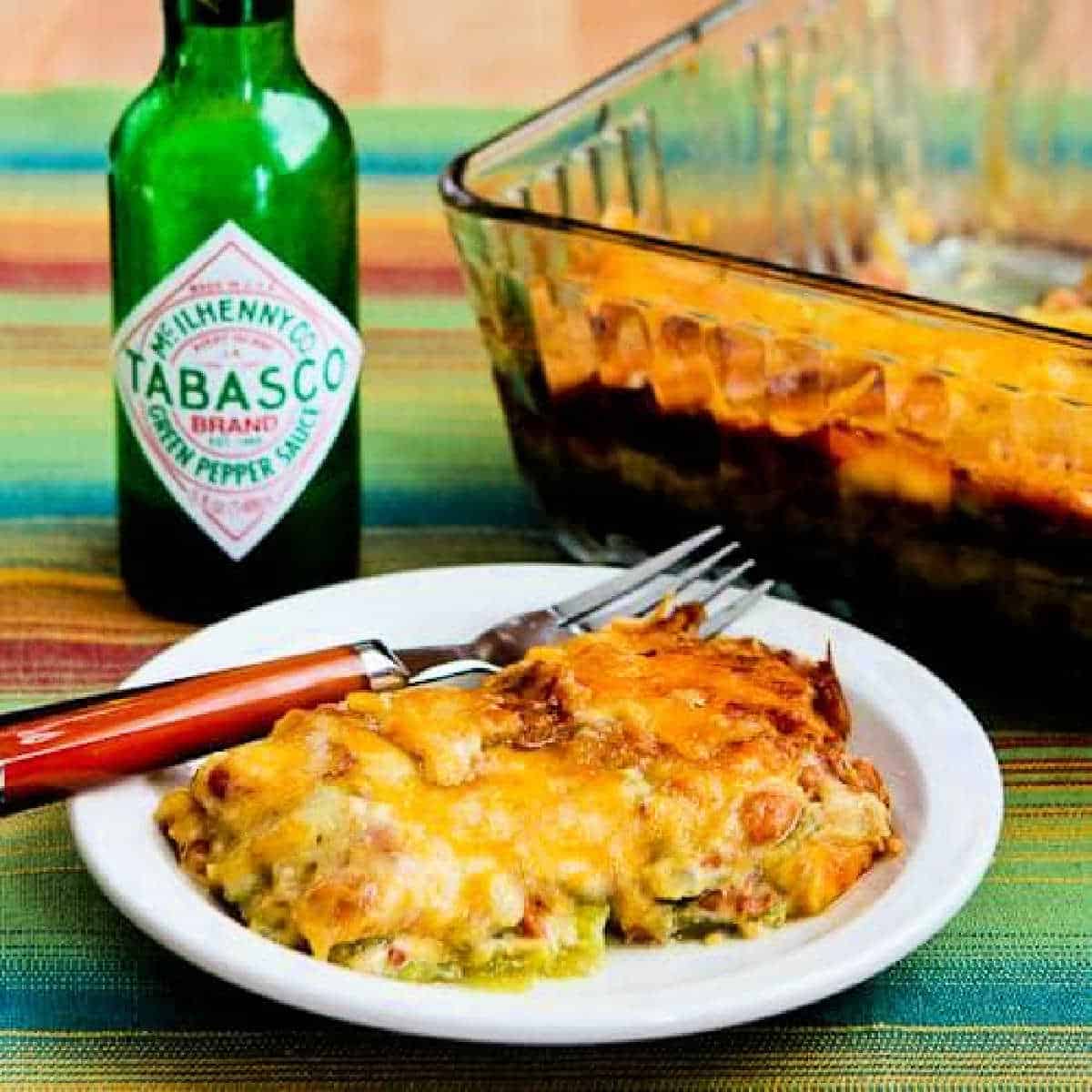 A square image of a vegetarian mexican casserole is displayed on a plate and the casserole is behind a baking dish.