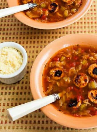Square image of Slow Cooker Cabbage Soup with Sausage shown in two bowls with Parmesan Cheese.