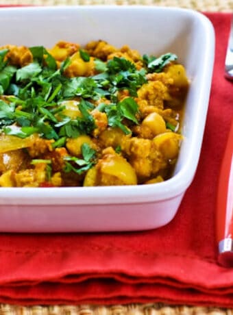 Turkey Curry with Chickpeas shown in square serving bowl on red napkin.