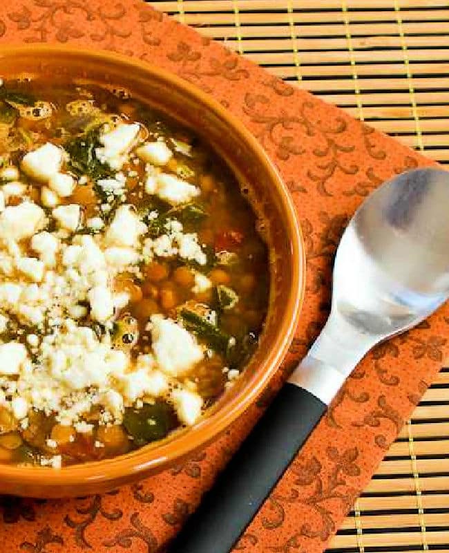 Slow Cooker Greek Lentil Soup in bowl with black spoon.