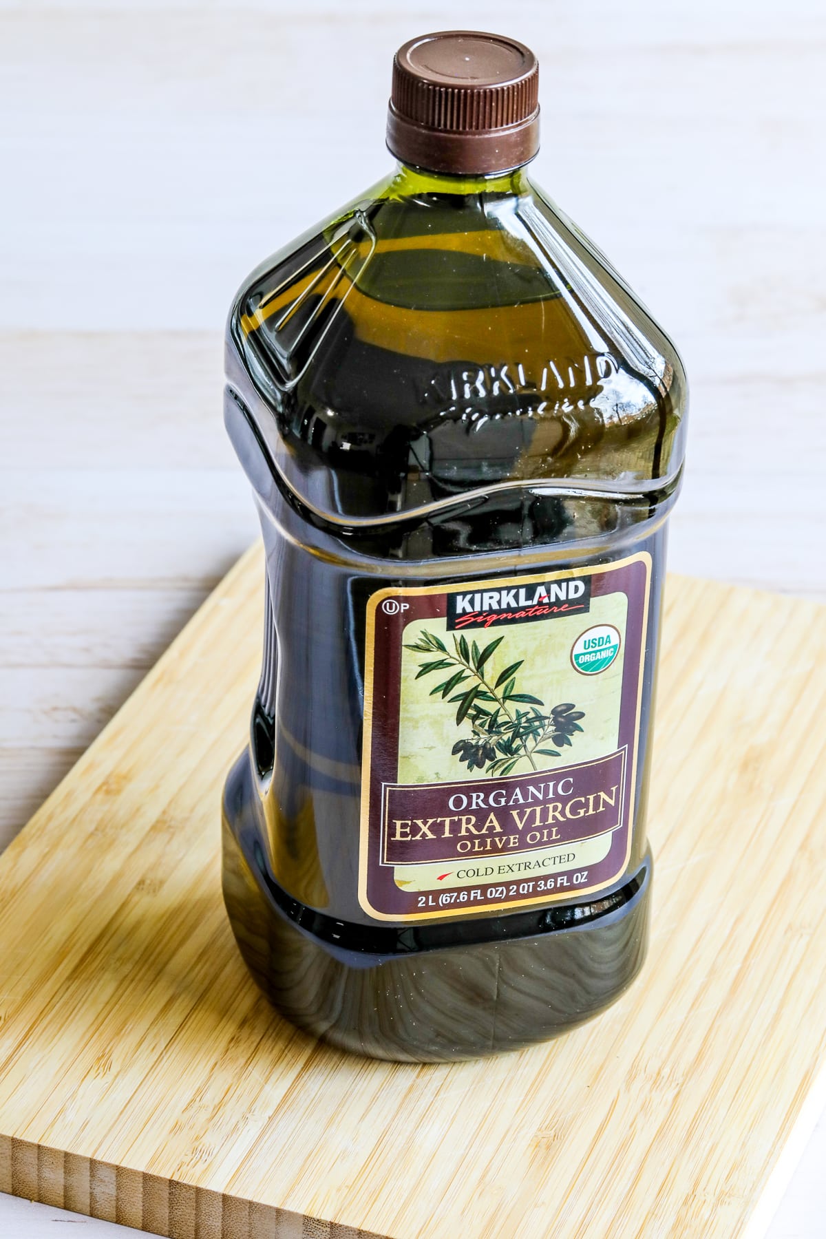 Kirkland Organic Extra-Virgin Olive Oil in bottle, shown on cutting board.