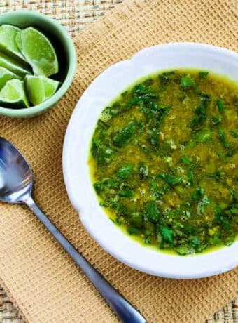 Square image for Indian Lentil Soup in bowl with limes and spoon.