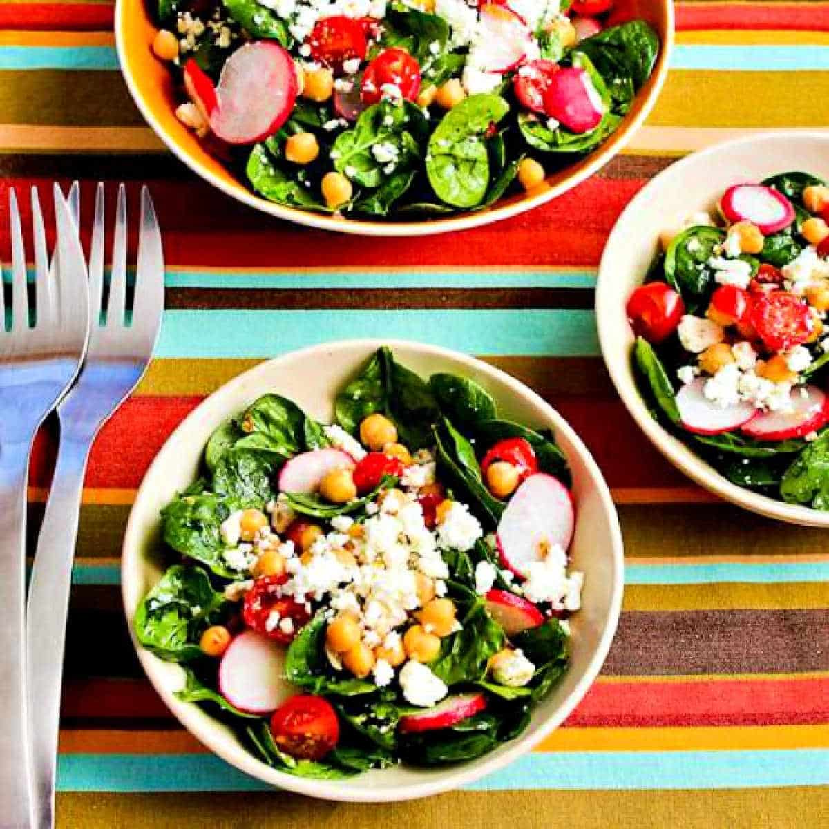 square image for Mediterranean Spinach Salad in three bowls with forks.