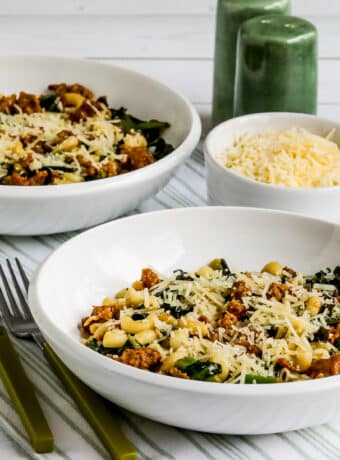 Square image of Italian Sausage Pasta with Collard Greens shown in two bowls.