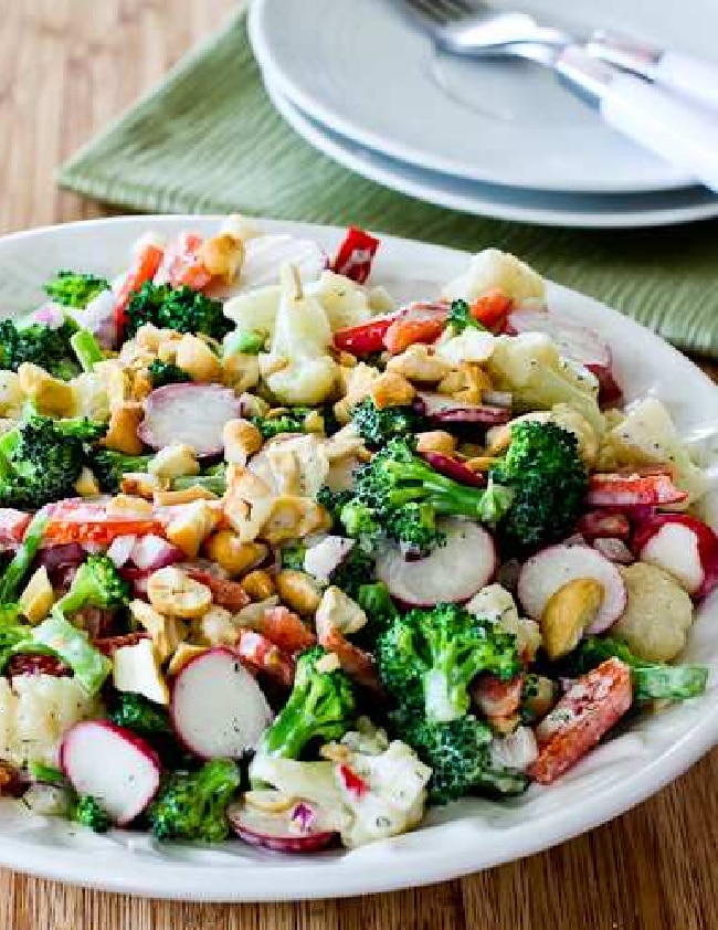 Broccoli, Cauliflower, and Radish Salad in serving bowl with plates and forks